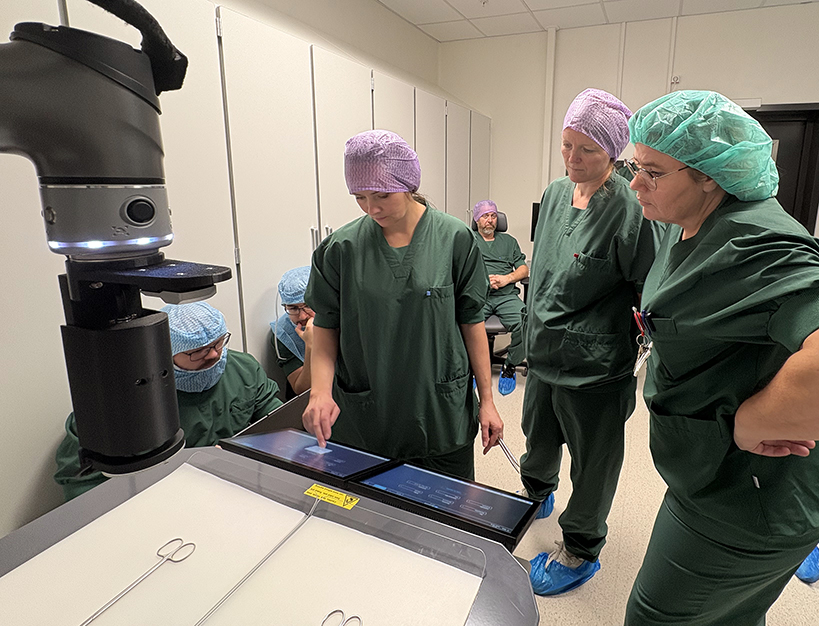 Ei gruppe menneske i kirurgiske uniformar som ser på ein skanner