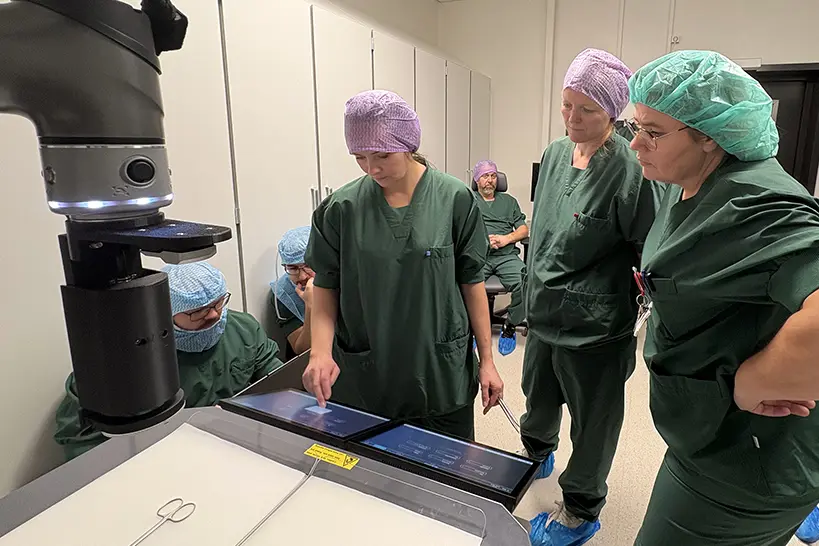 Ei gruppe menneske i kirurgiske uniformar som ser på ein skanner