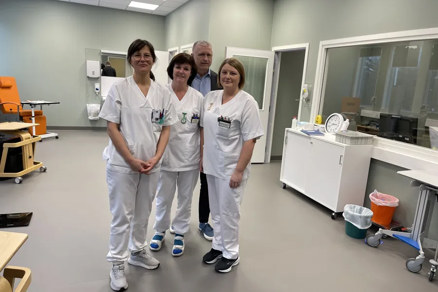 En gruppe mennesker i hvite labfrakker som står i et rom