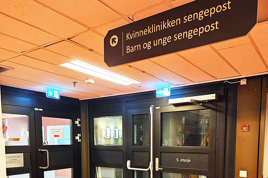 Bilde frå gangen inn til kvinneklinikken, med skilt som viser veg
