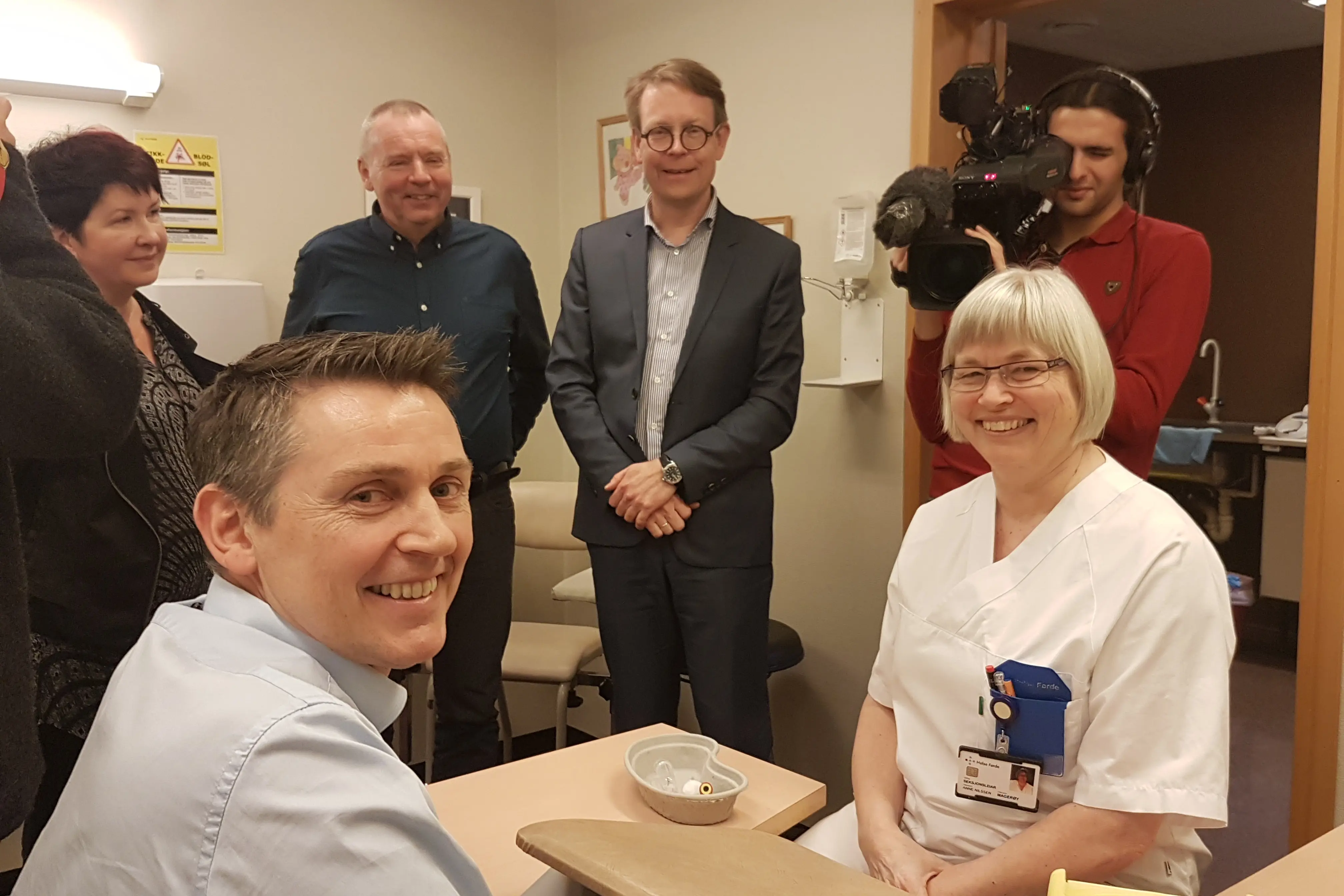 Ei rekke personar som står og sit rundt eit bord på sjukehuset