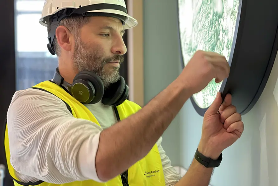 Ein kunstnar som monterer eit kunstverk