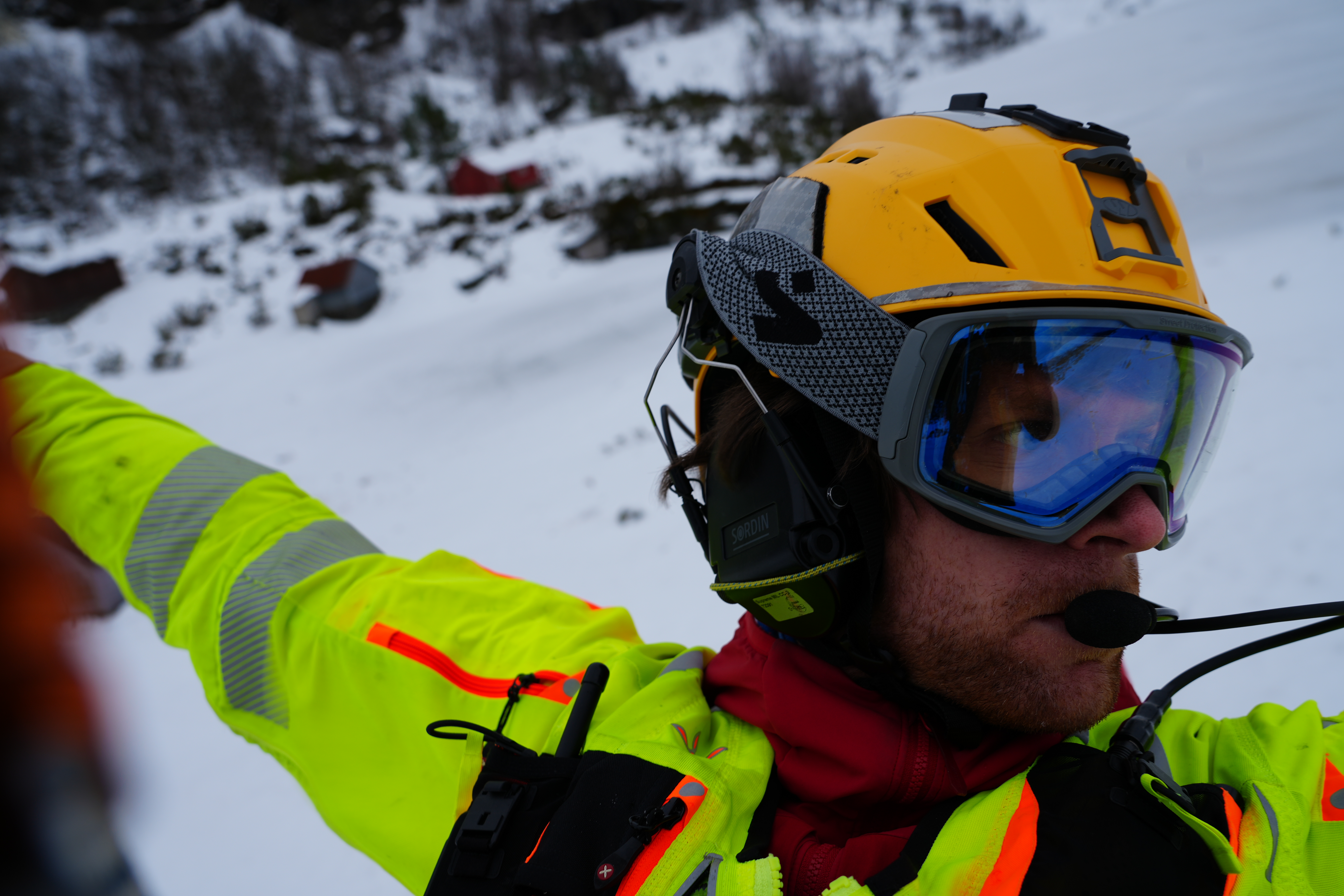 Nærilde av redningsmann med hjelm hengande utanfor luftambulansen