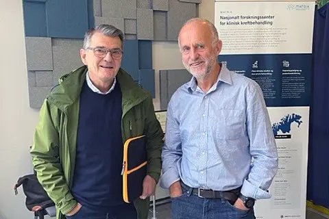 Et par menn poserer for kameraet