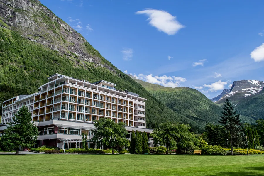 Hotel Alexandra i Loen med fjell og blå himmel i bakgrunnen