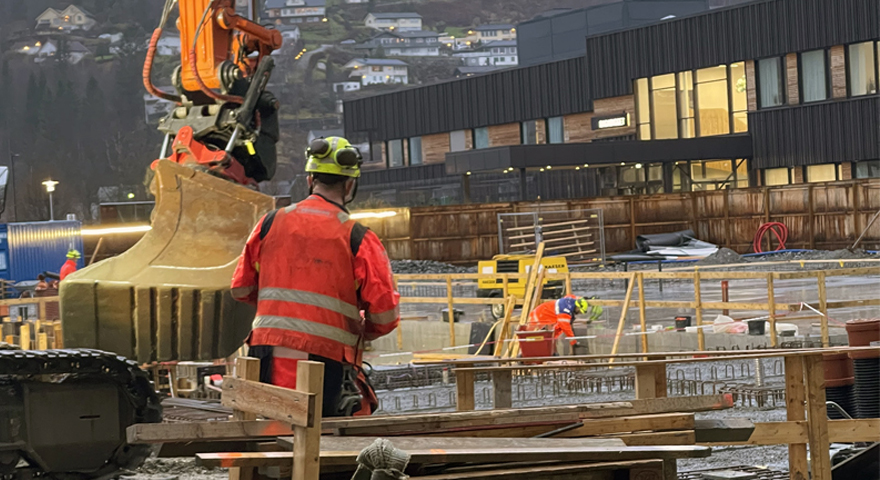 Bildet viser ein byggeplass med arbeidarar og maskiner