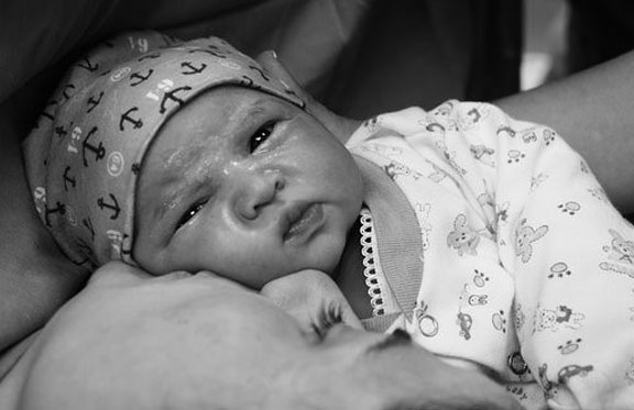 Svart-kvitt bilde av ein nyfødd baby saman med mor