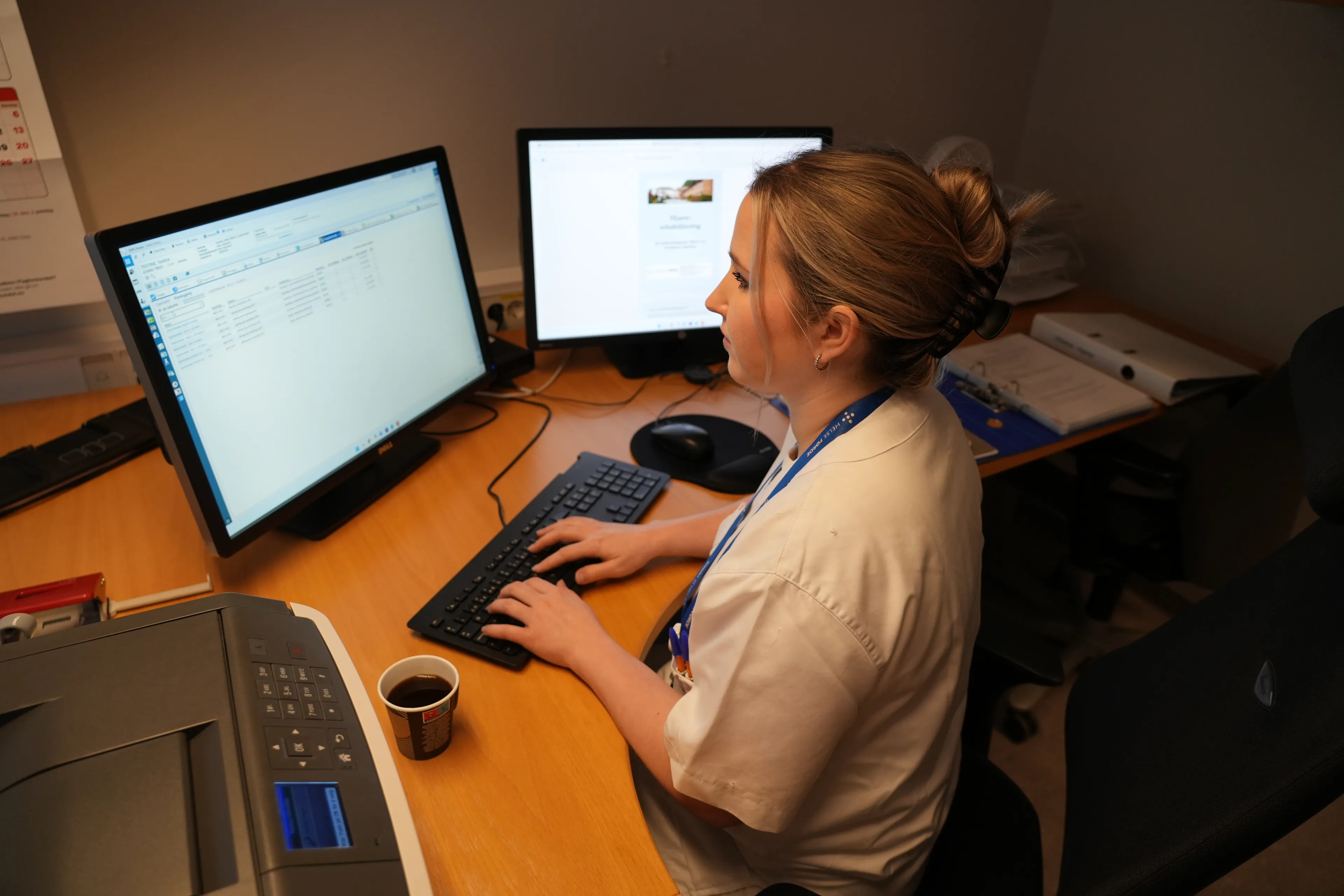 Ei kvinneleg helsesekretær som sit å jobbar ved datamaskina
