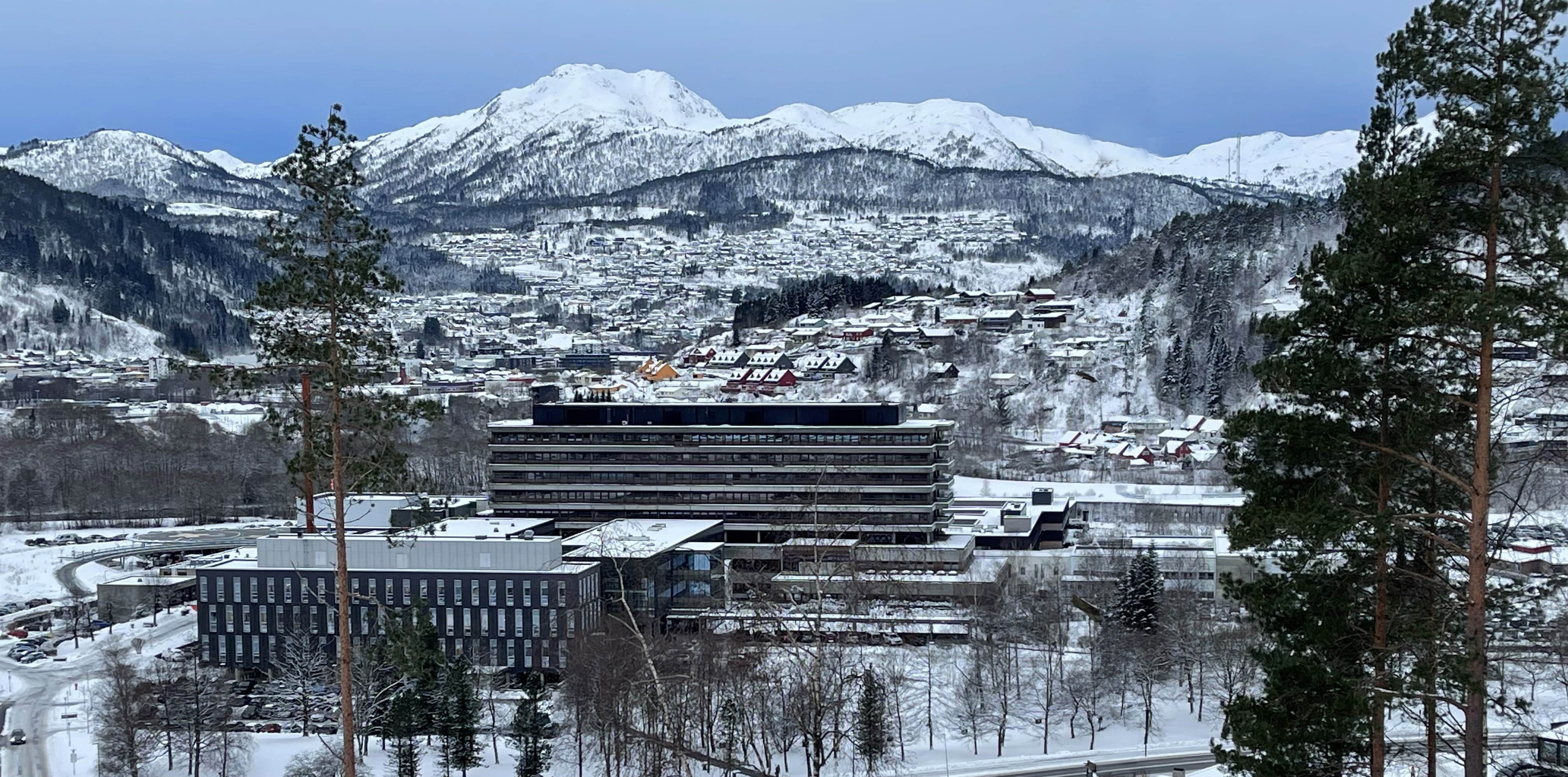 Oversiktsbilde av Førde sentralsjukehus ein vinterdag med snødekte fjell i bakgrunnen
