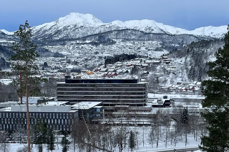 Oversiktsbilde av Førde sentralsjukehus ein vinterdag med snødekte fjell i bakgrunnen