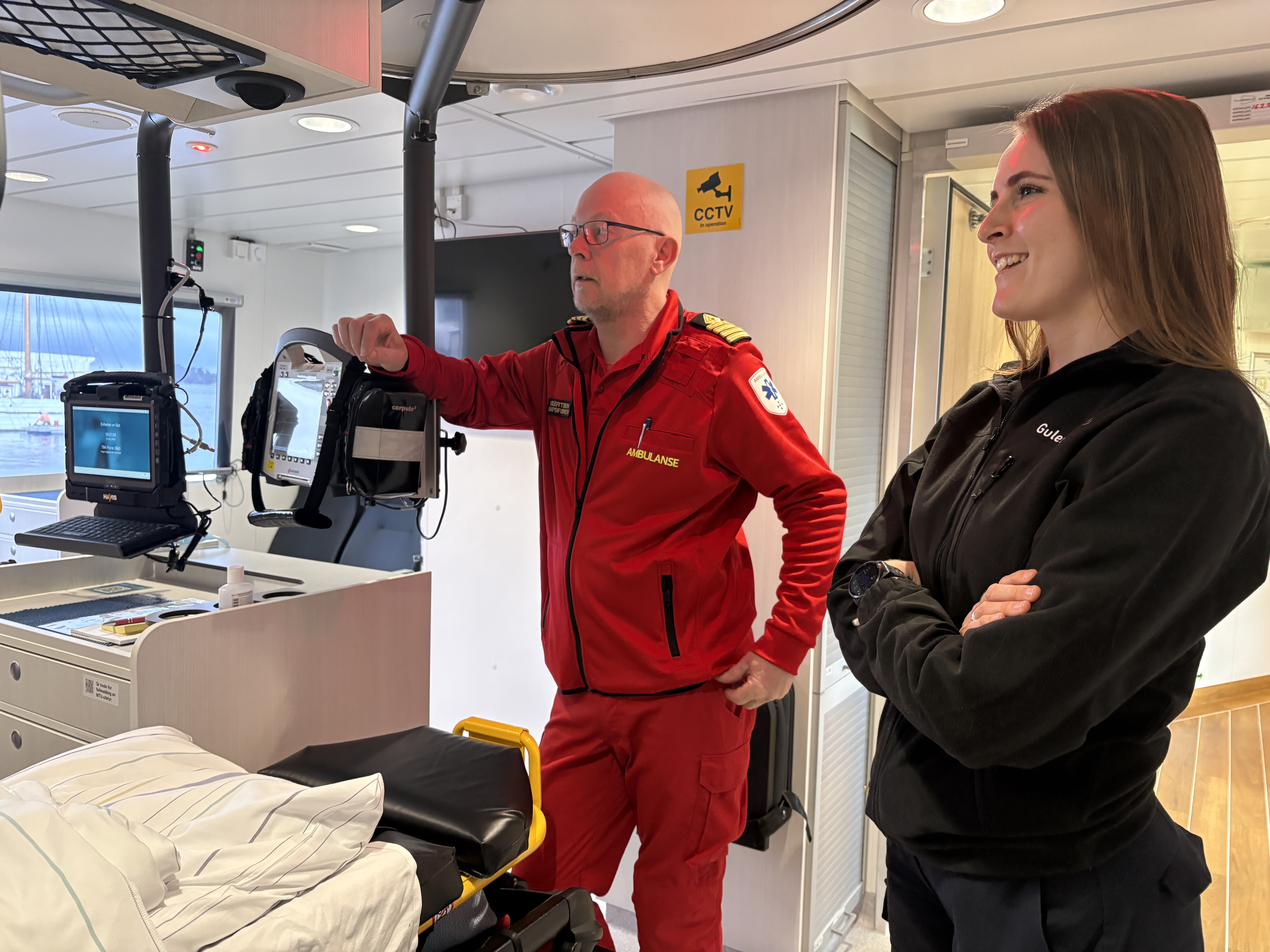 Ein mann og ei kvinne i uniformar ombord i ambulansebåten