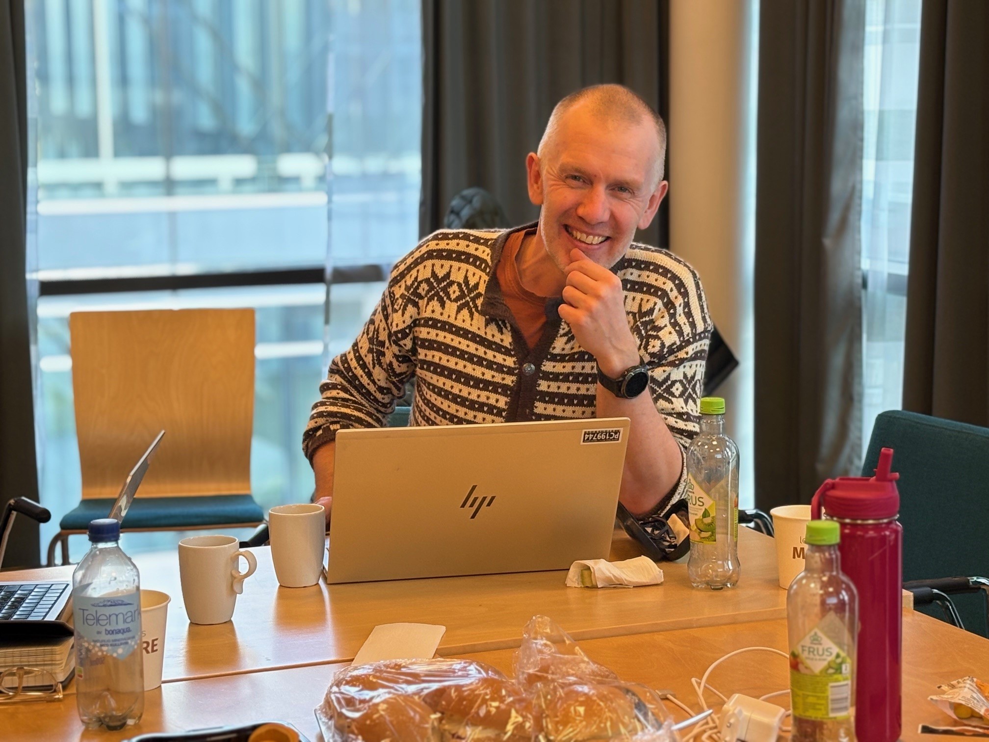 Ein person som sit ved eit bord med ein bærbar PC
