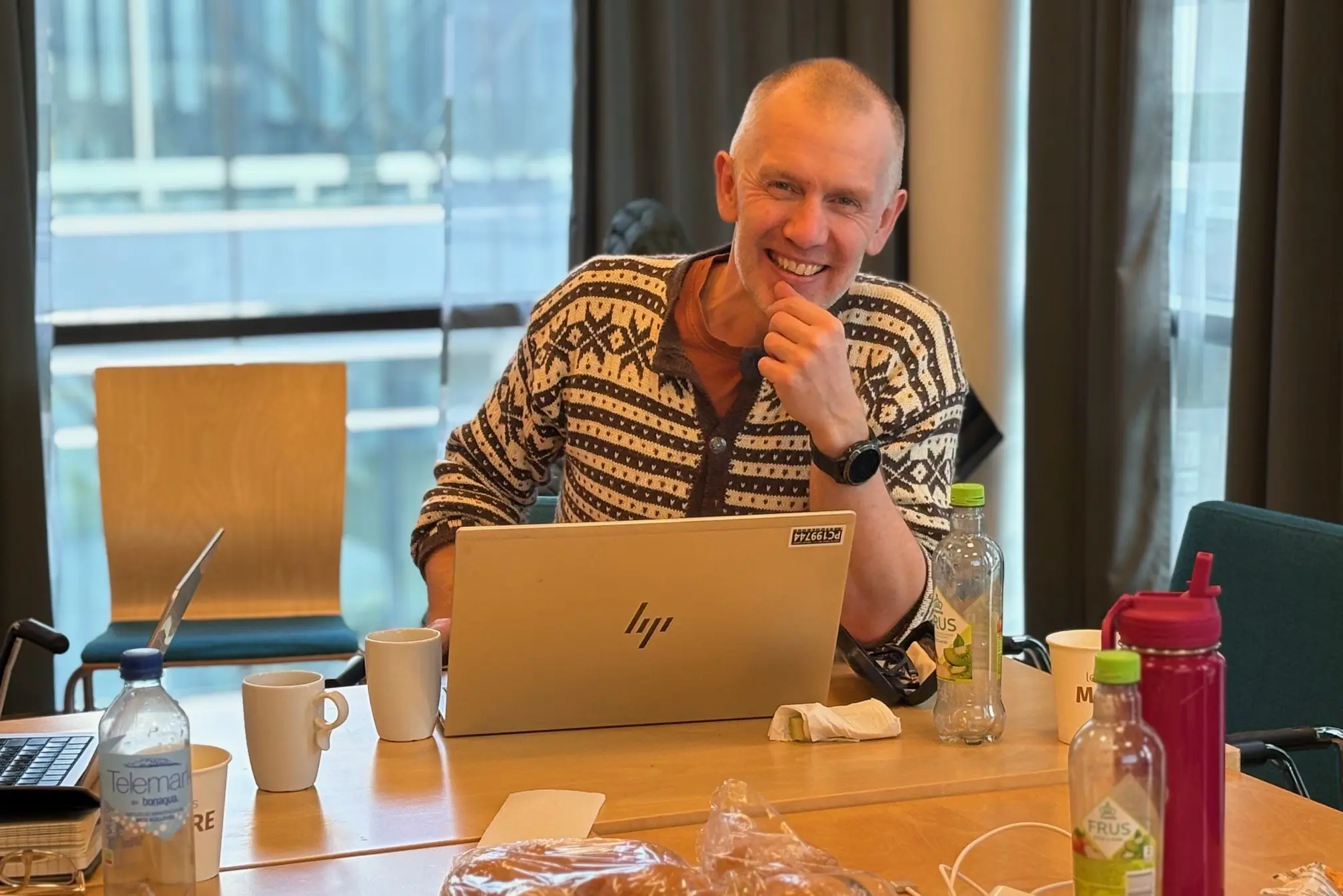 Ein person som sit ved eit bord med ein bærbar PC