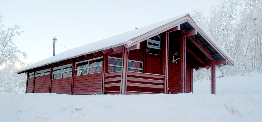En rødmalt hytte i et vinterlandskap