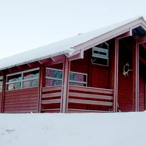 En rødmalt hytte i et vinterlandskap