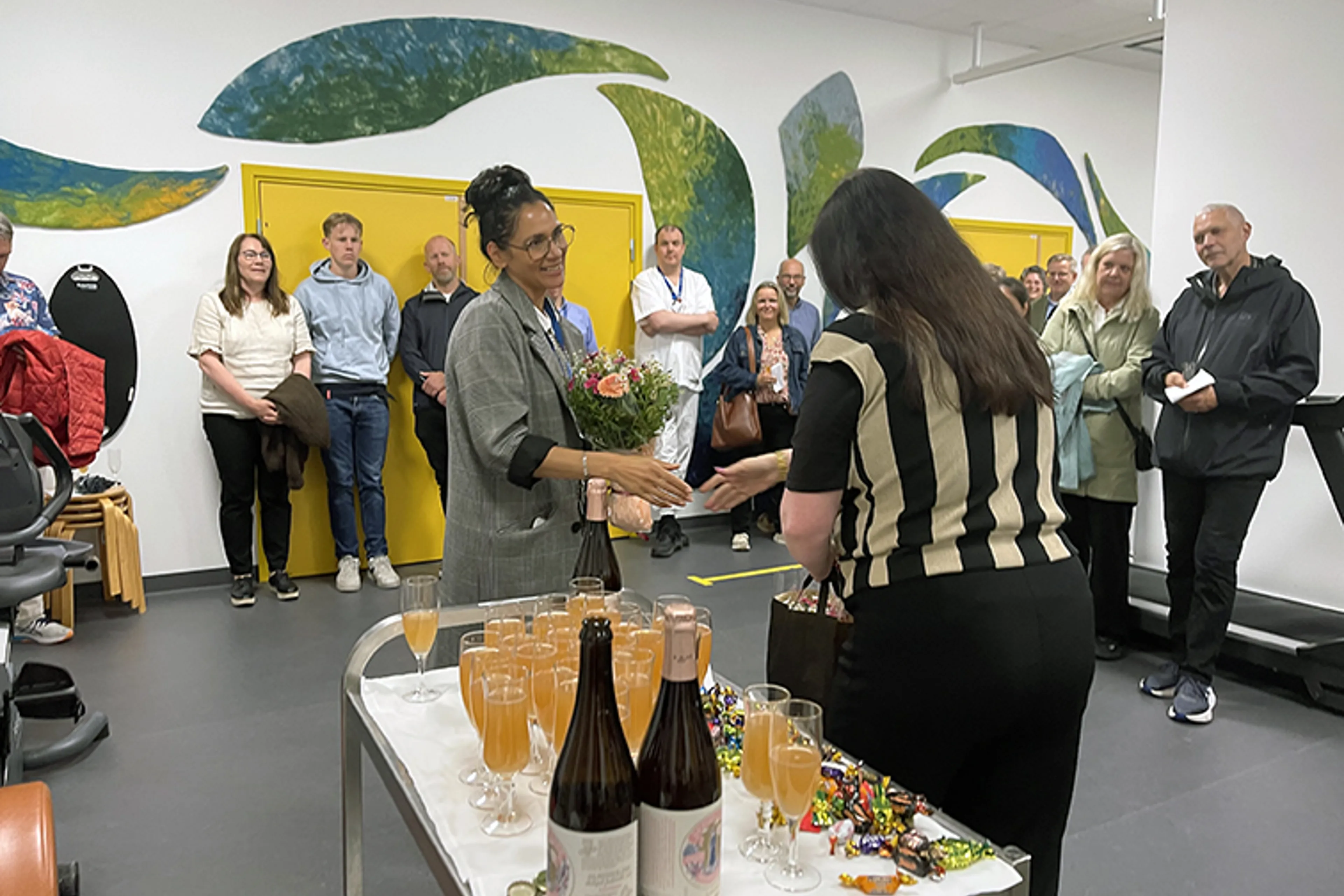 En gruppe mennesker som står rundt et bord med vinflasker