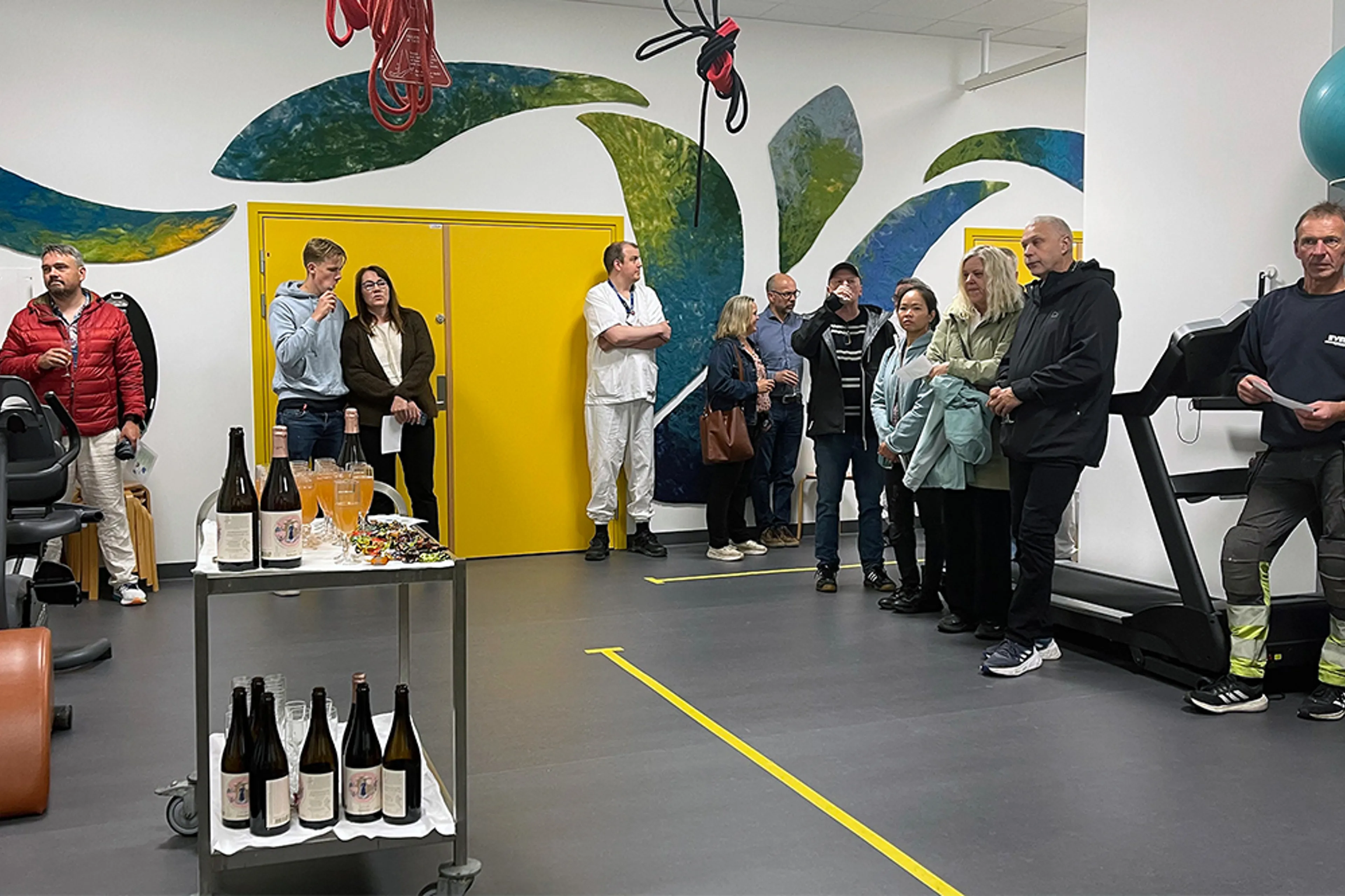 En gruppe mennesker som står i et rom med vinflasker