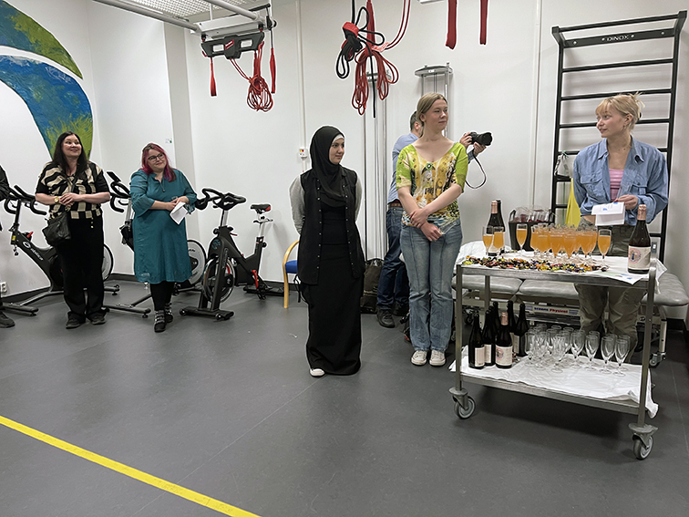 Ei gruppe mennesker som står i eit rom med bord med mat og drikke