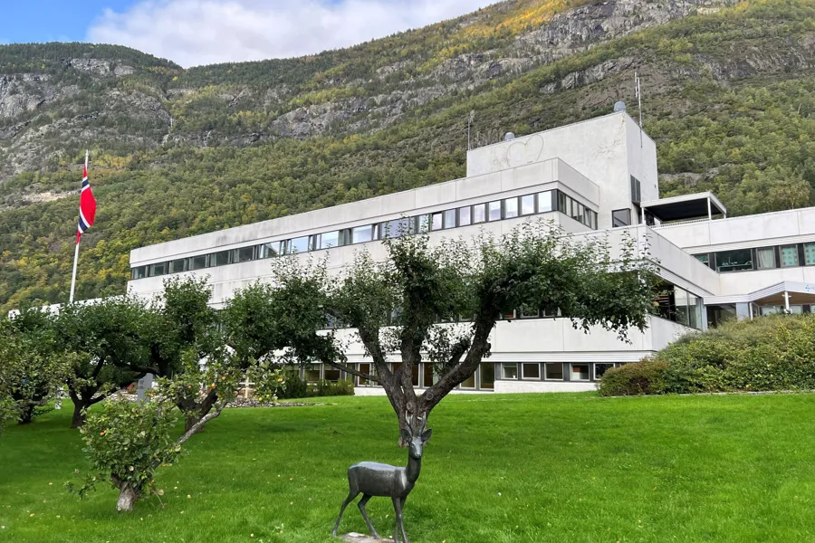 En statue av en hjort foran en bygning med et fjell i bakgrunnen