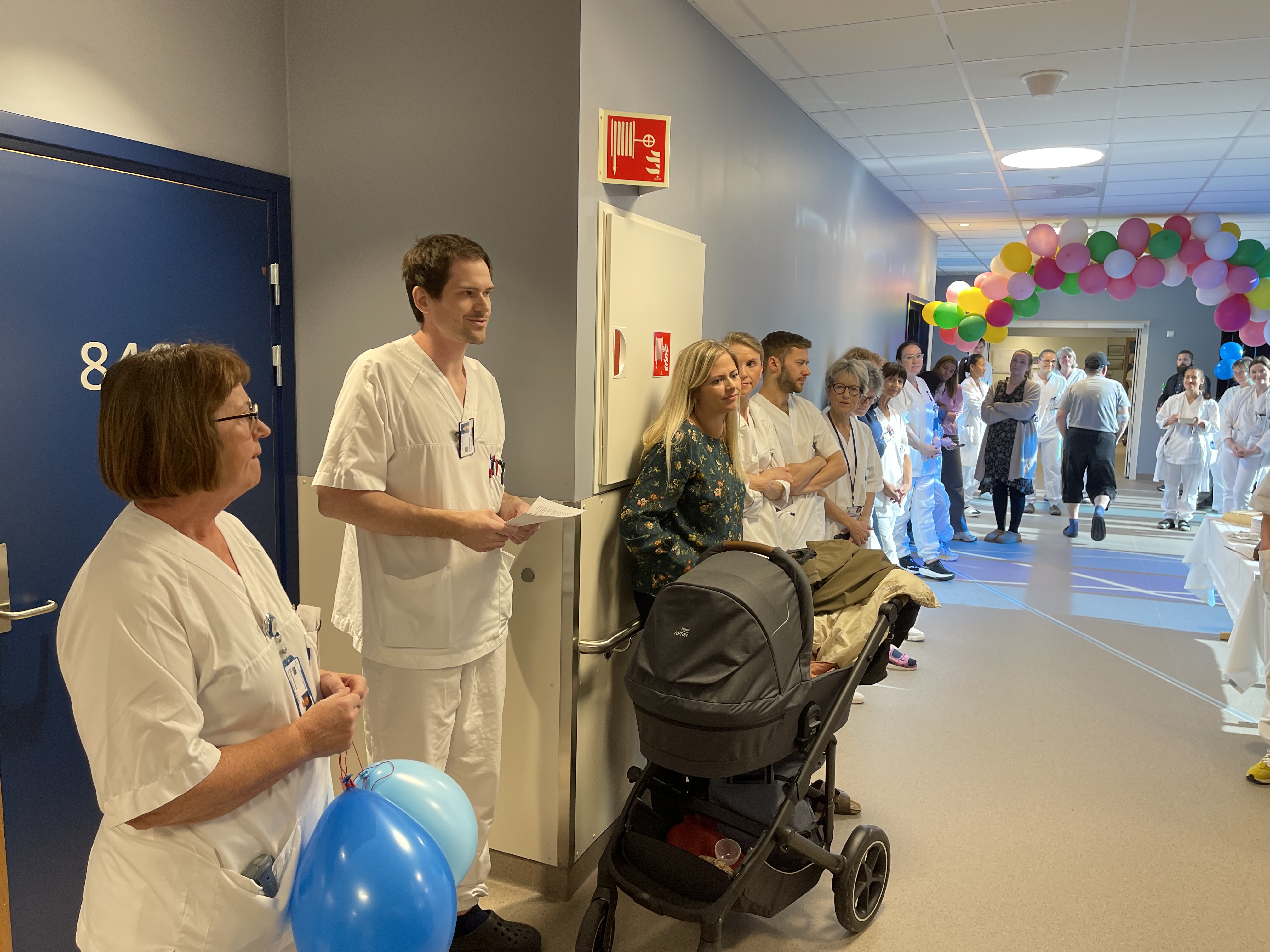 En gruppe personer i kledd i hvite helsepersonelluniformer i et rom med ballonger