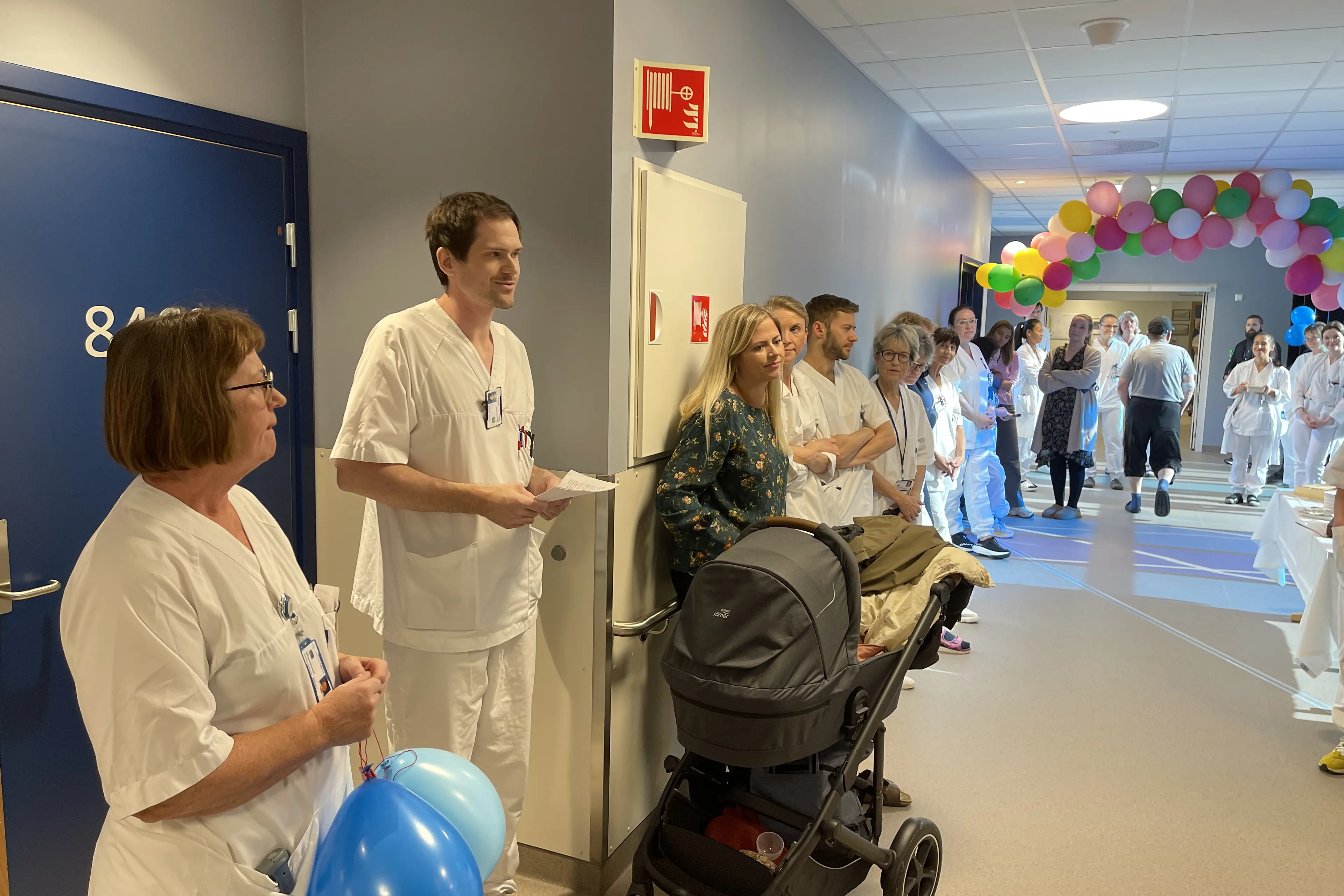 En gruppe personer i kledd i hvite helsepersonelluniformer i et rom med ballonger