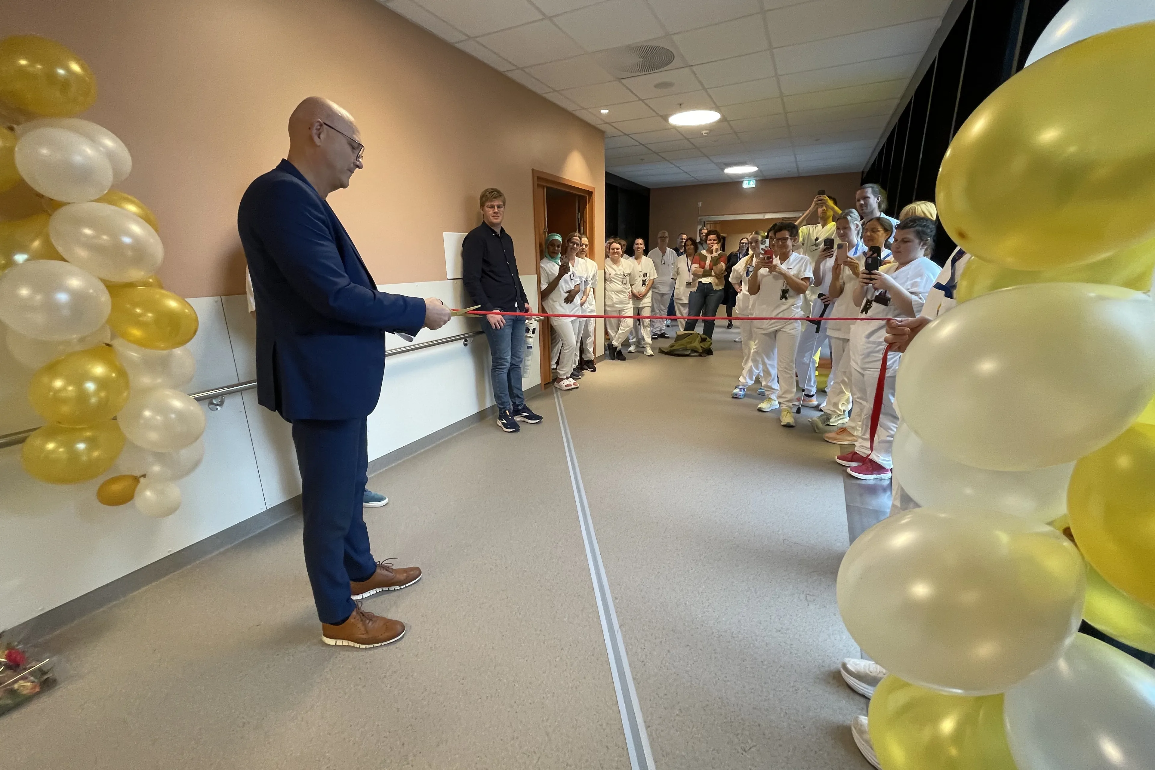 Administerende direktør Arve Varden gjør seg klar til å klippe snoren i 7. etasje. Ansatte følger med, og det er pyntet med ballonger.