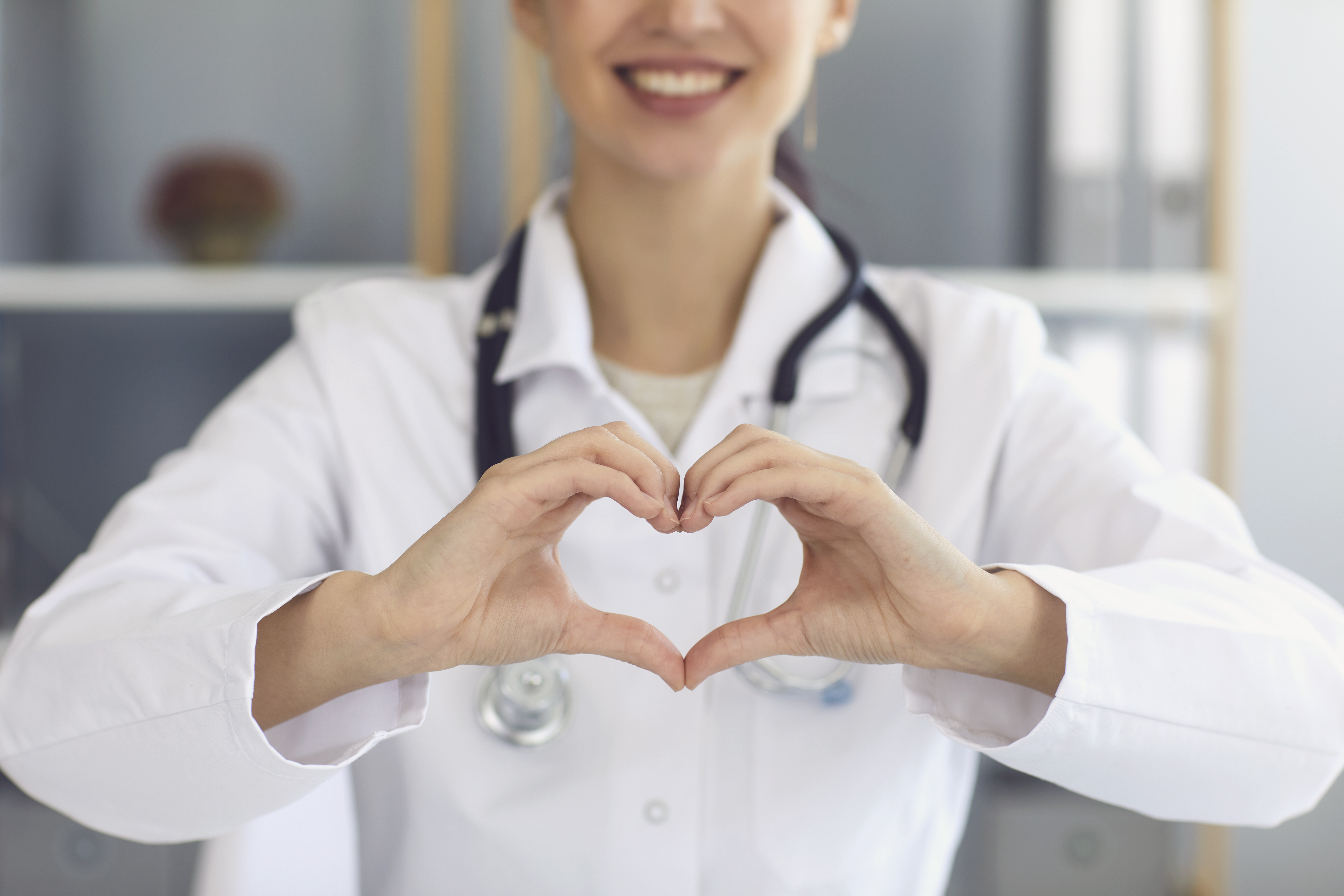 Ein lege i kvit frakk som lagar eit hjerte med hendene sine