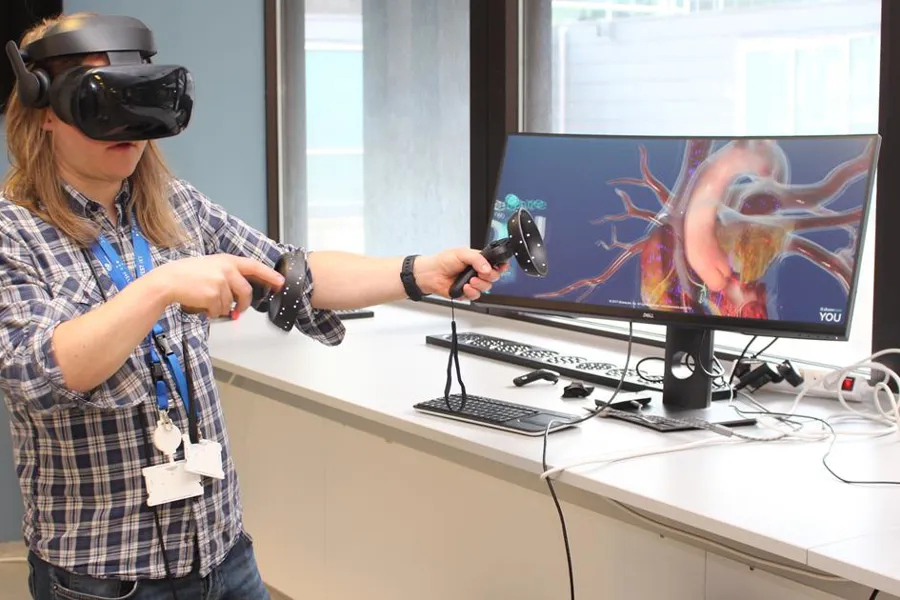 En person som har på seg et headset og holder en mikrofon foran en dataskjerm