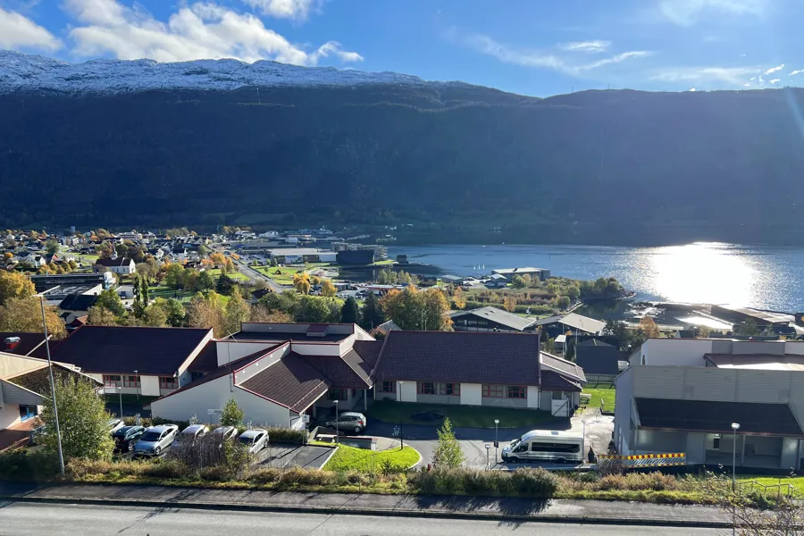 Nordfjord psykiatrisenter sett ovanfrå, med Eid sentrum og fjella i bakgrunnen.
