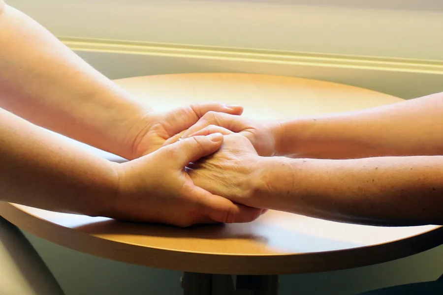 Nærbilde av to personar som held hender