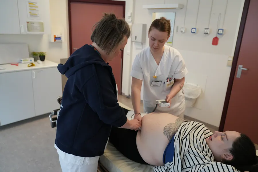 Ei jordmor og ein jordmorstudent undersøker ei gravid kvinne