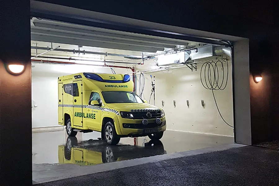 Ein gul ambulansebil parkert i ein garasje