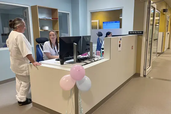 To tilsette i kvite uniformar i samtale ved ein kontorpult i den nye poliklinikken