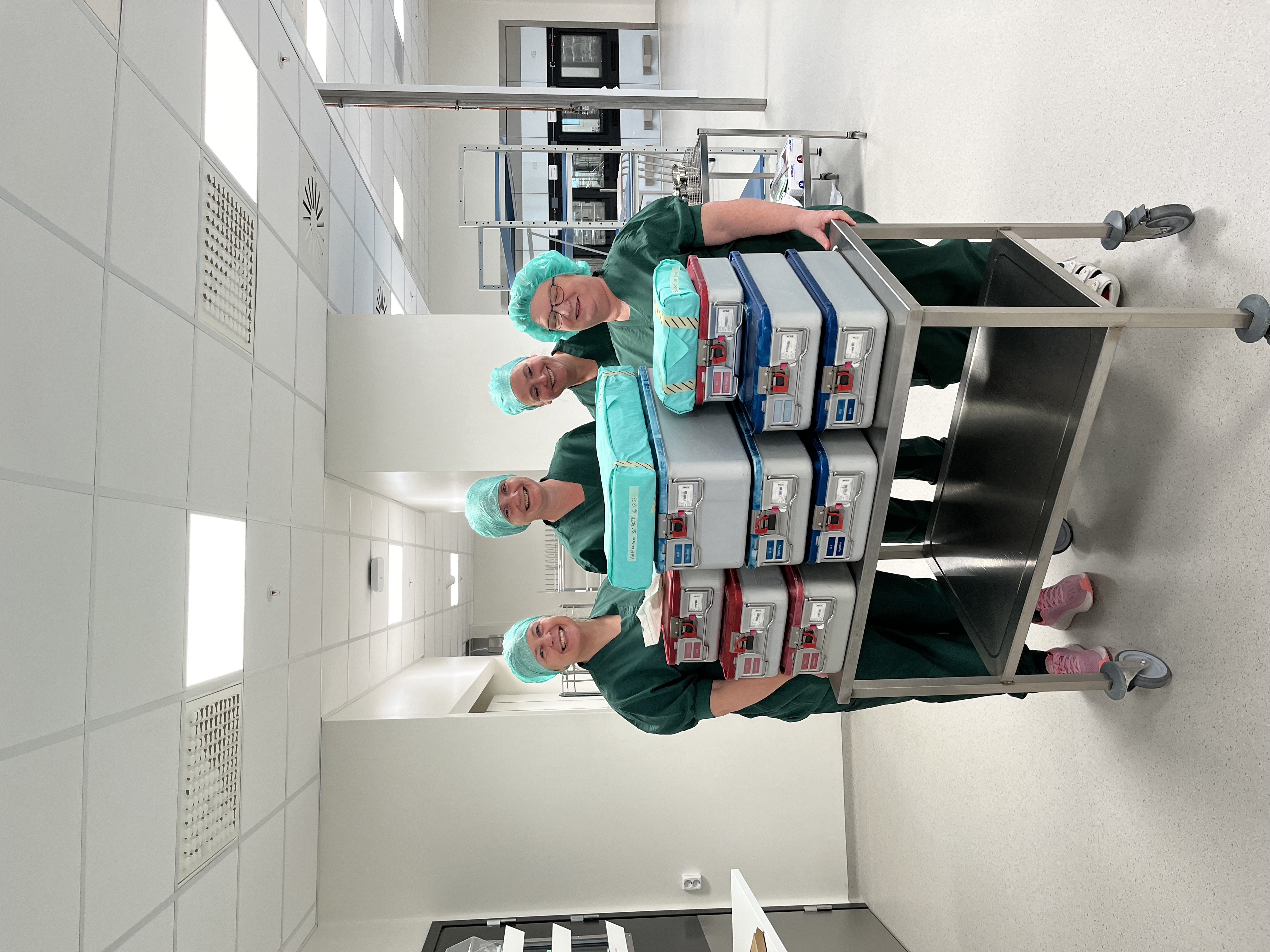 En gruppe kvinner i kirurgiske skrubb i et rom med en vogn full av medisinsk utstyr