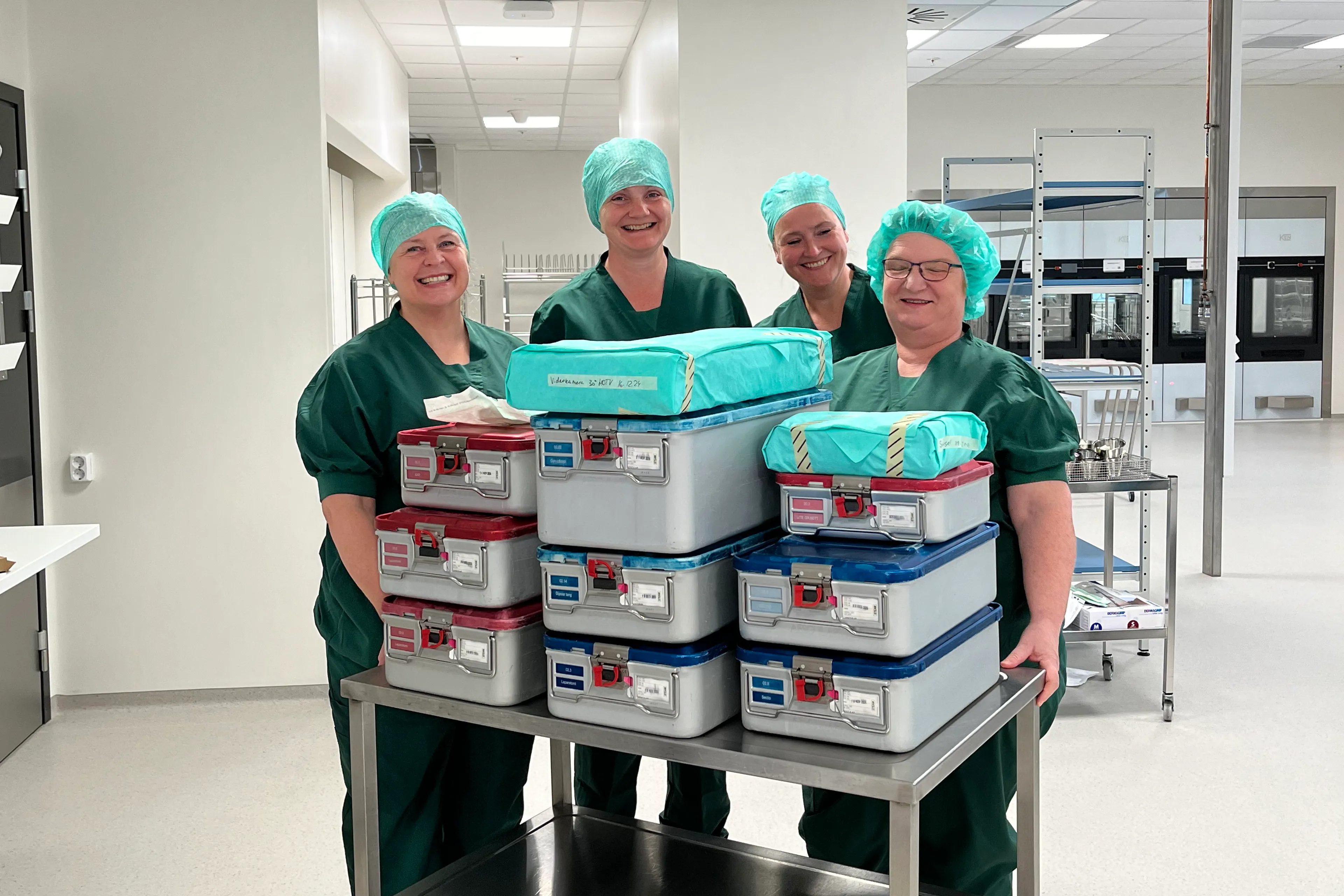 Grønkledde kvinner med hette på hodet som står foran en tralle