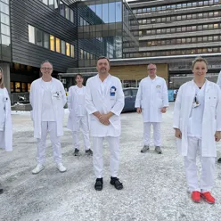 Sju kvitkledde legar som står samla utanfor sentralblokka