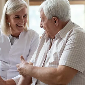 Ei kvinne og ein eldre mann som smiler og pratar