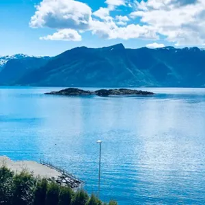 Fjord og fjellandskap som badar i sommarsol