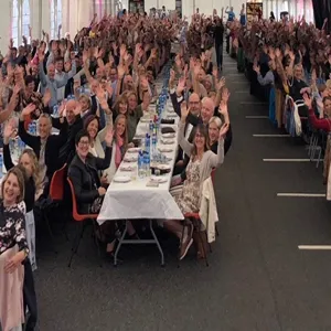 ei stor samling av glade mennesker som sit rundt langbord