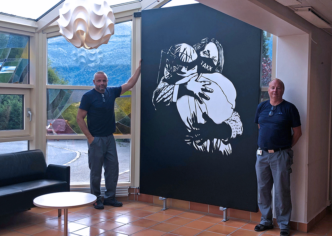 bilde av to menn som står ved sidan av eit stort bilde av to personar som omfavnar kvarandre