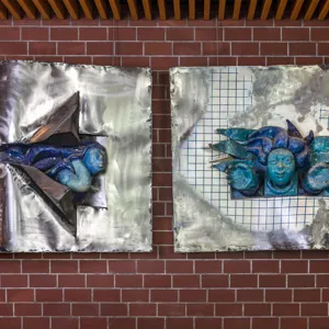 kunstverk i stål metall og keramikk som heng på ein mursteinsvegg