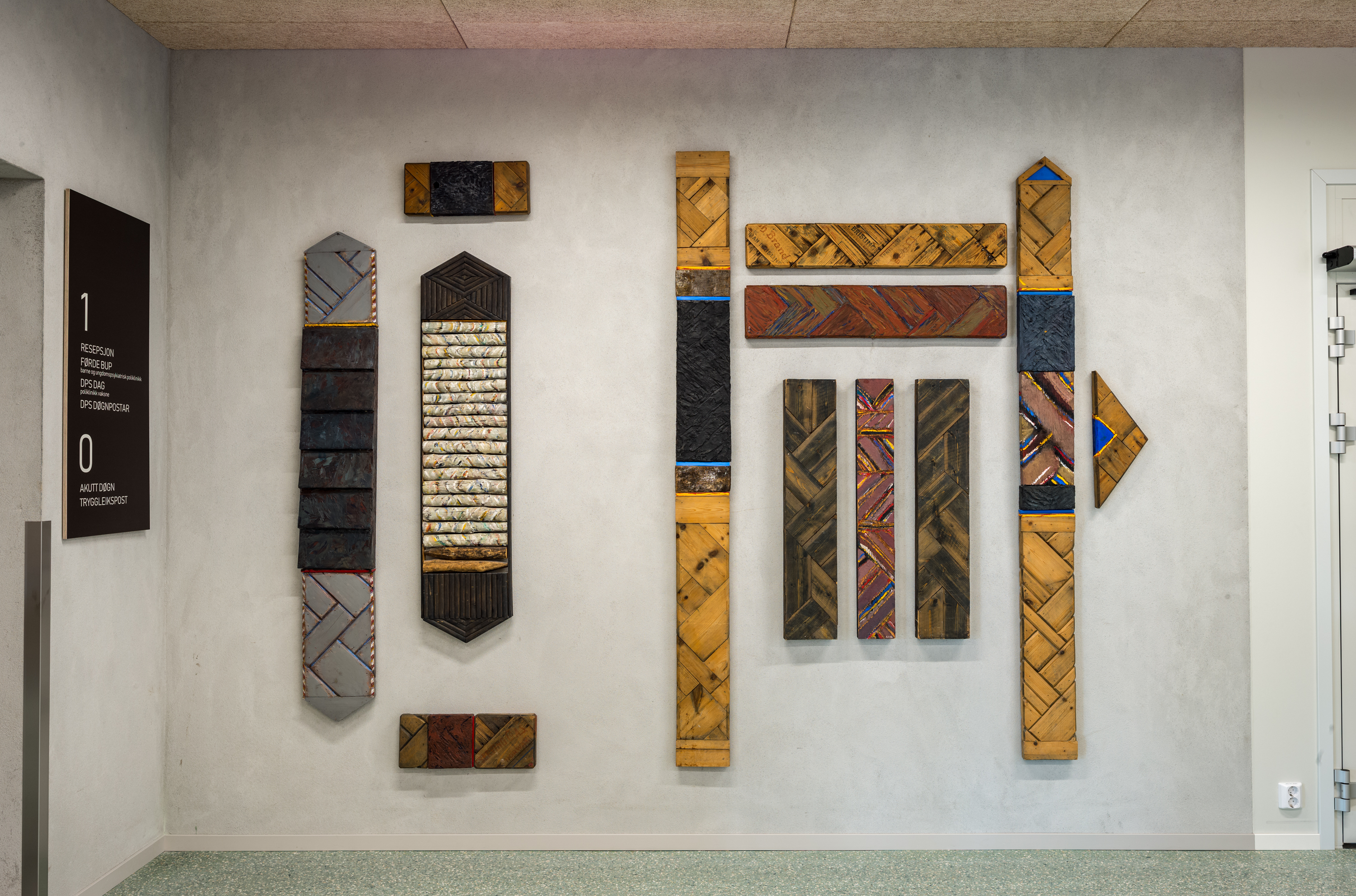 betongvegg med trefigurar i ulik storleik og former