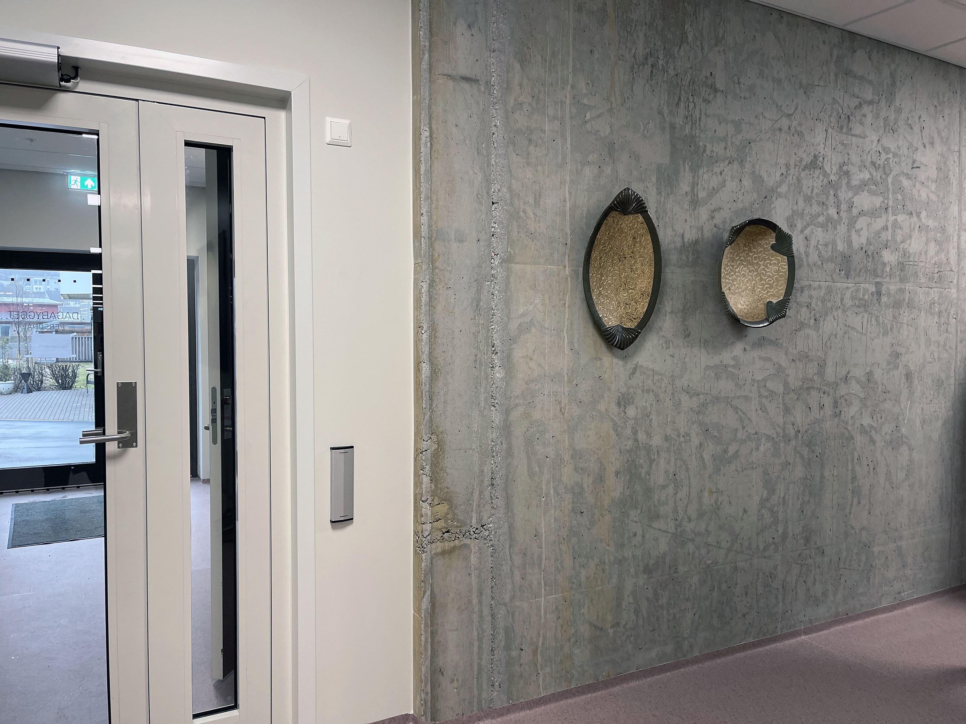 betongvegg med to keramikkfat i svart og gull som heng på veggen