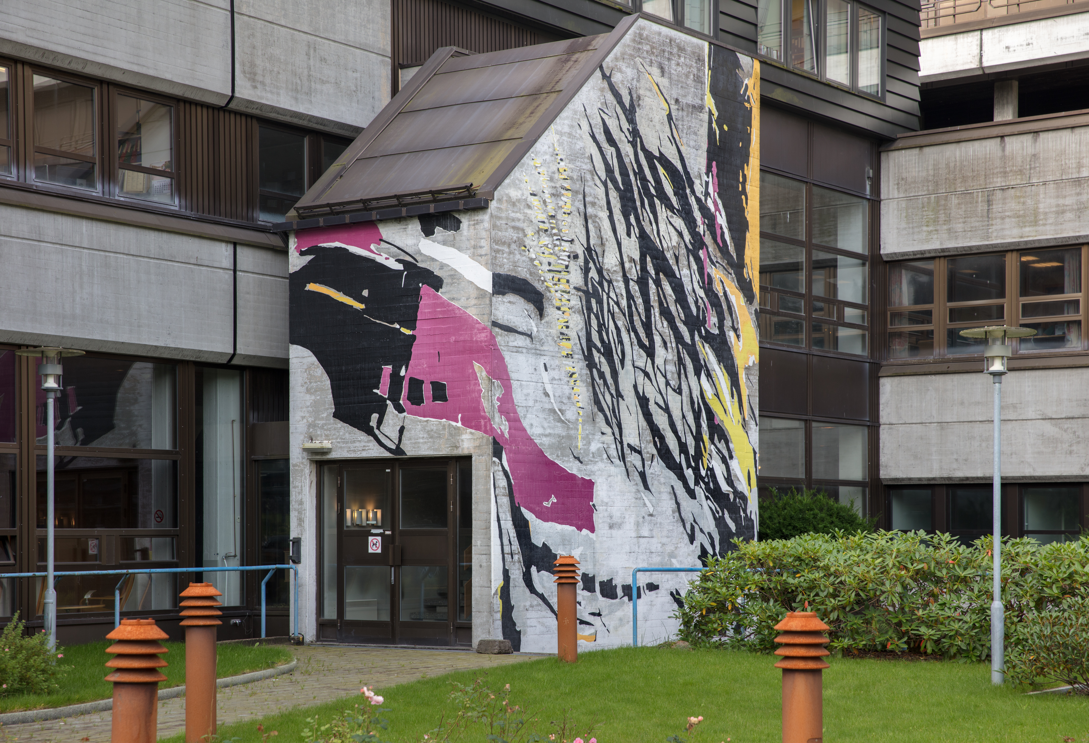 Betongbygning med kunstverk i rosa, gult og svart måla på veggen