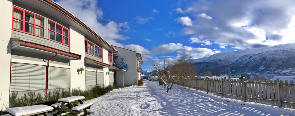 En bygning med gjerde og snødekte fjell i bakgrunnen