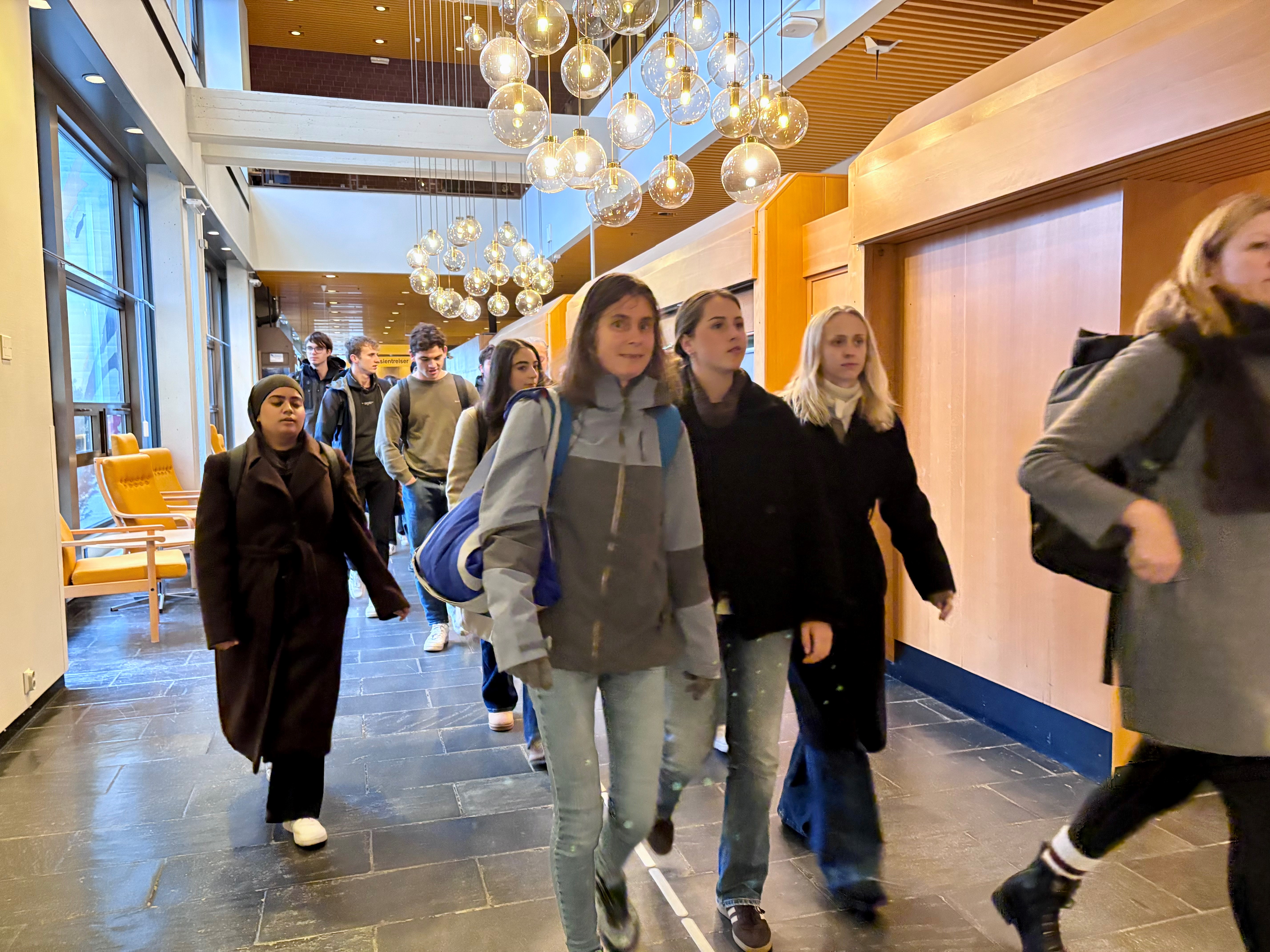 Ei gruppe menneske på farten i ein korridor