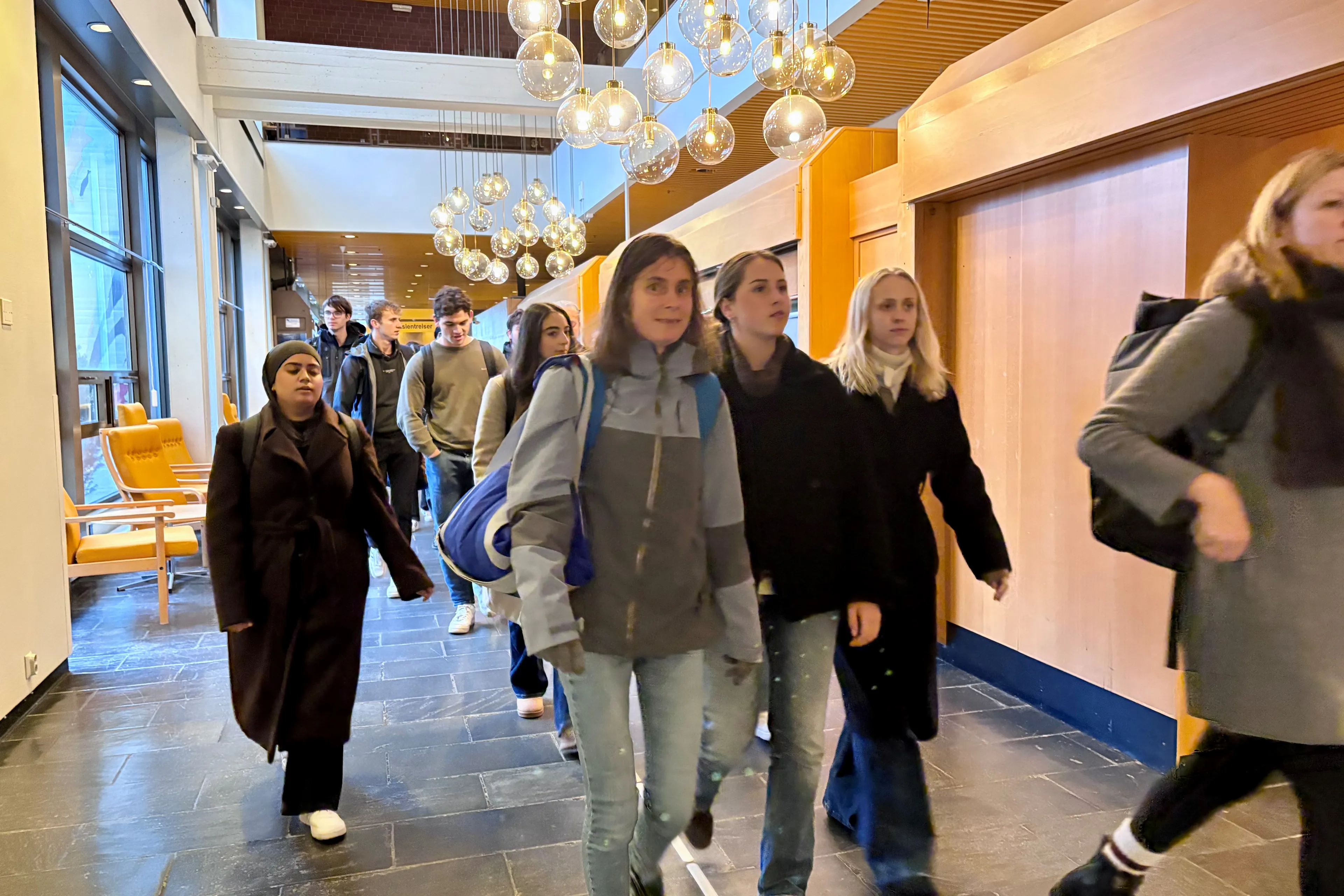 Ei gruppe menneske på farten i ein korridor