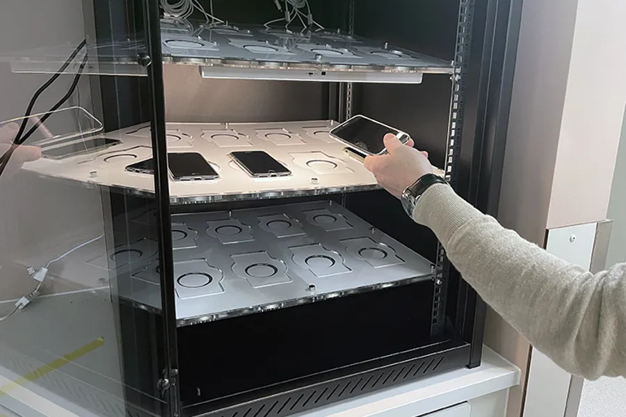 Ein person som står framfor eit ladeskap for mobiltelefonar