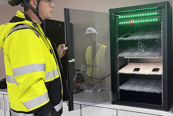 Ein person står framfor eit ladeskap for mobiltelefonar