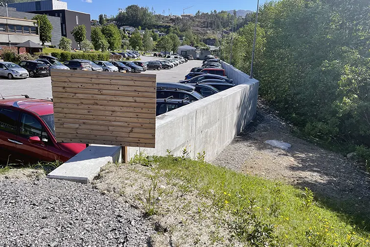 Ein parkeringsplass med bilar og ein betongmur